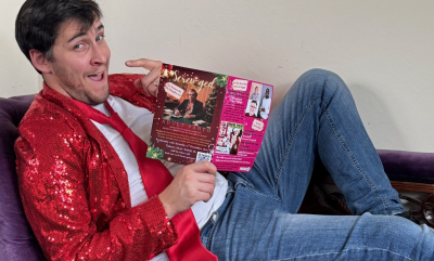 A man lying on a chaise longe holding a flyer and pointing at himself