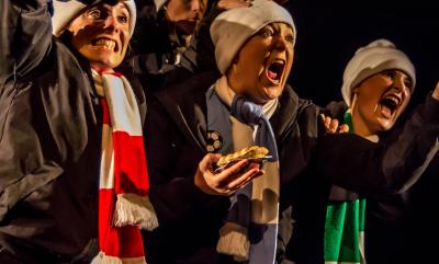 The 'Next Door Dance' cast of The Beautiful Game on stage shouting and screaming..