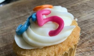 A cupcake topped with an iced number five.