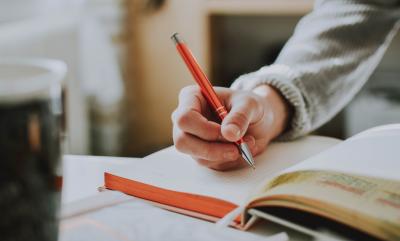 A person writing in a pad with a pen.