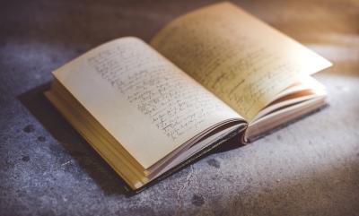 Old book with cursive writing on stone brick, being slightly lit