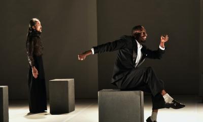 Two men dancing within a black box theatre
