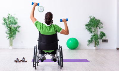 A wheelchair user holding weights and exercising at a Disability Arts: Music & Movement class.