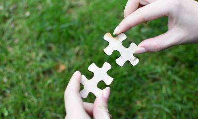 a person connecting two puzzle pieces together on grass