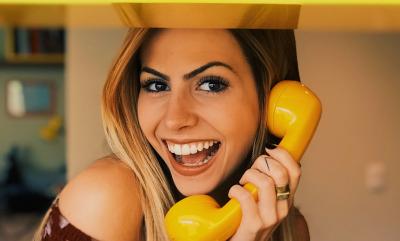 A smiling lady talking on a bright yellow phone.