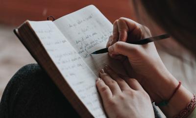 Lady writing in a book with a pen