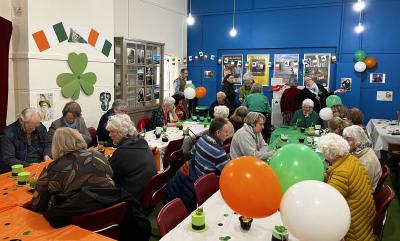 People sat around tables in a room with Irish coloured decorations