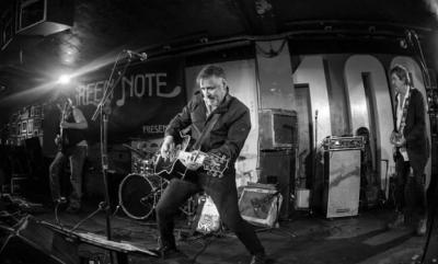 Micky Kemp playing his guitar on a stage