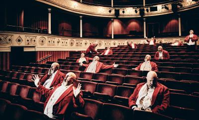 Lots of the same magician sitting in theatre seats