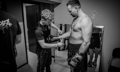 A young man helping an older man put on boxing gloves