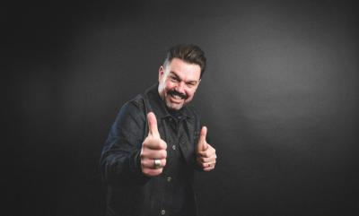 A man giving thumbs up against a black background