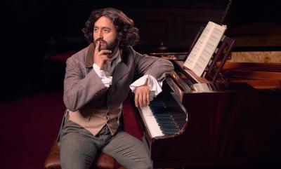 A man in a wig by a piano