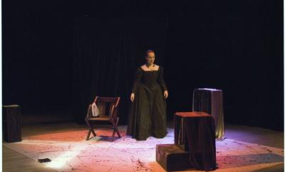 A woman in a tudor black dress on a stage