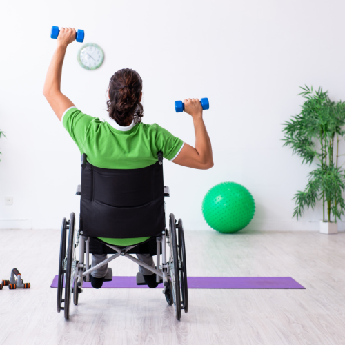 A wheelchair user holding weights and exercising at a Disability Arts: Music & Movement class.