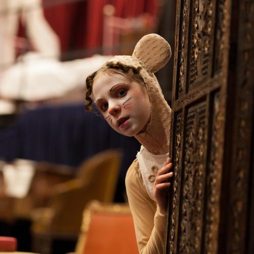Girl in mouse costume learning out from a wardrobe