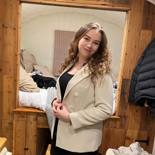 Amy Wheeler wearing a cream jacket looking in a mirror